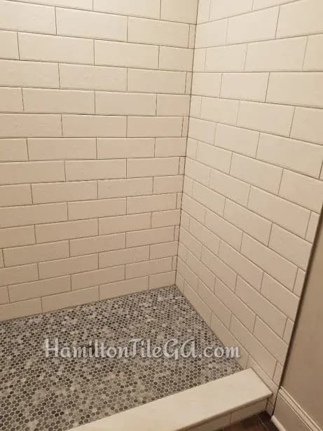 Love this combination. Penny Rounds and embossed 4x12's. Dark grout Brushed nickle with solid curb. The shower is edged with brushed nickle Jolly profiles. Notice the drain! A lot nicer than a basic builder grade piece! Tile purchased from Tradition…